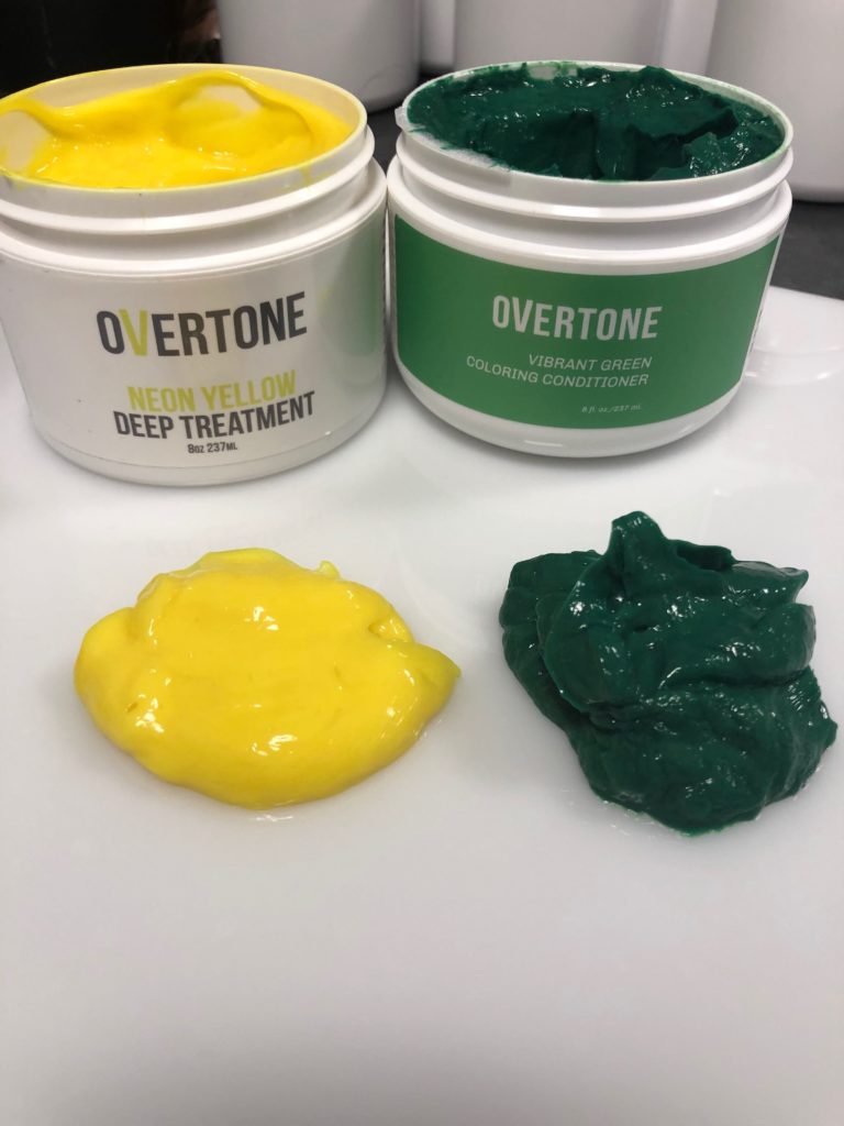 A container of oVertone Coloring conditioners in Neon Yellow and Vibrant green with accompanying dollops of product.  